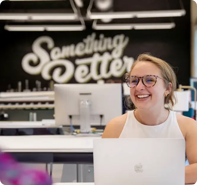 Melanie smiling at work station - Something Better Graphic in the background - thumbnail image